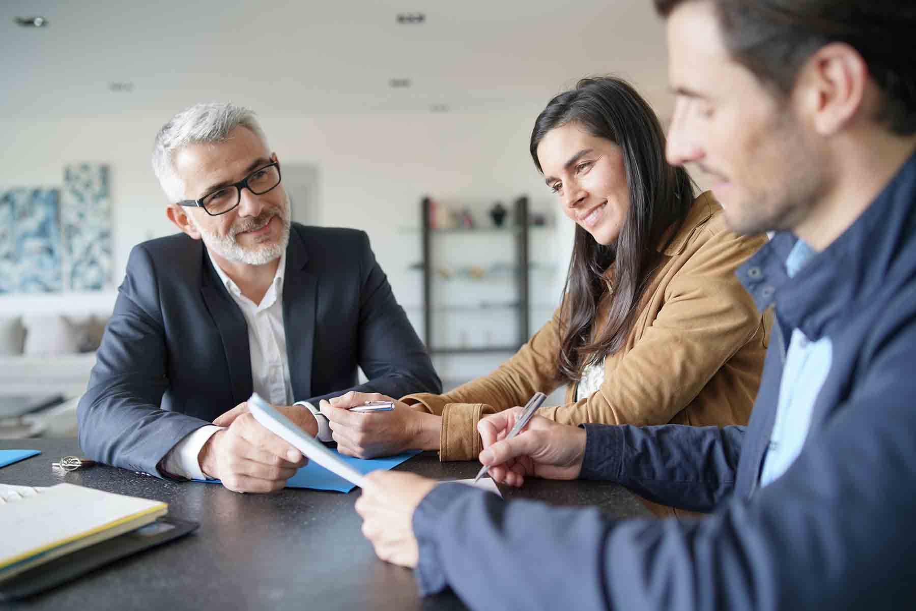 Attractive couple signing contract with real-estate agent in co Attractive couple signing contract with real-estate agent in contemporary house