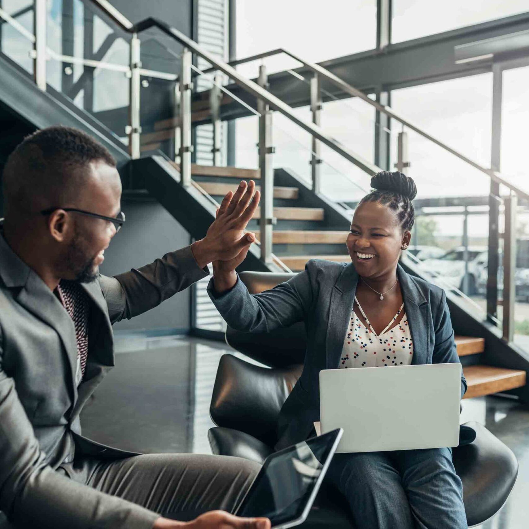 Two friendly smiling african business people celerbarting their sucess with a high five